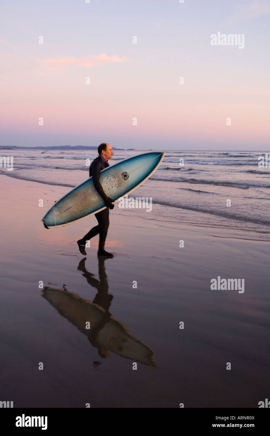 Surfer geht Küstenlinie, Pacific Rim National Park, Long Beach, Vancouver Island, British Columbia, Kanada. Stockfoto
