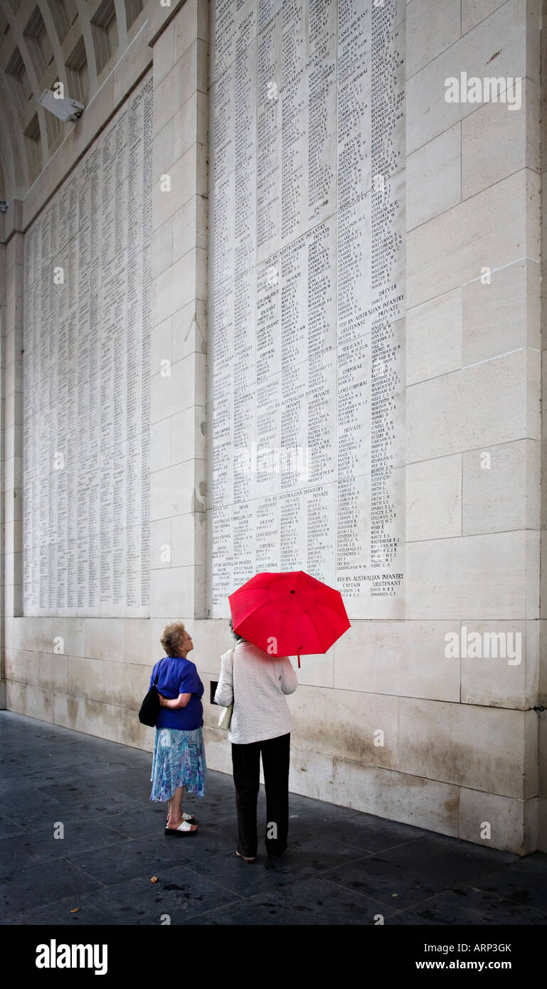 Zwei Frauen mit roten Regenschirm lesen Namen des Krieges tot in Menin Gate Ypern, Belgien Stockfoto