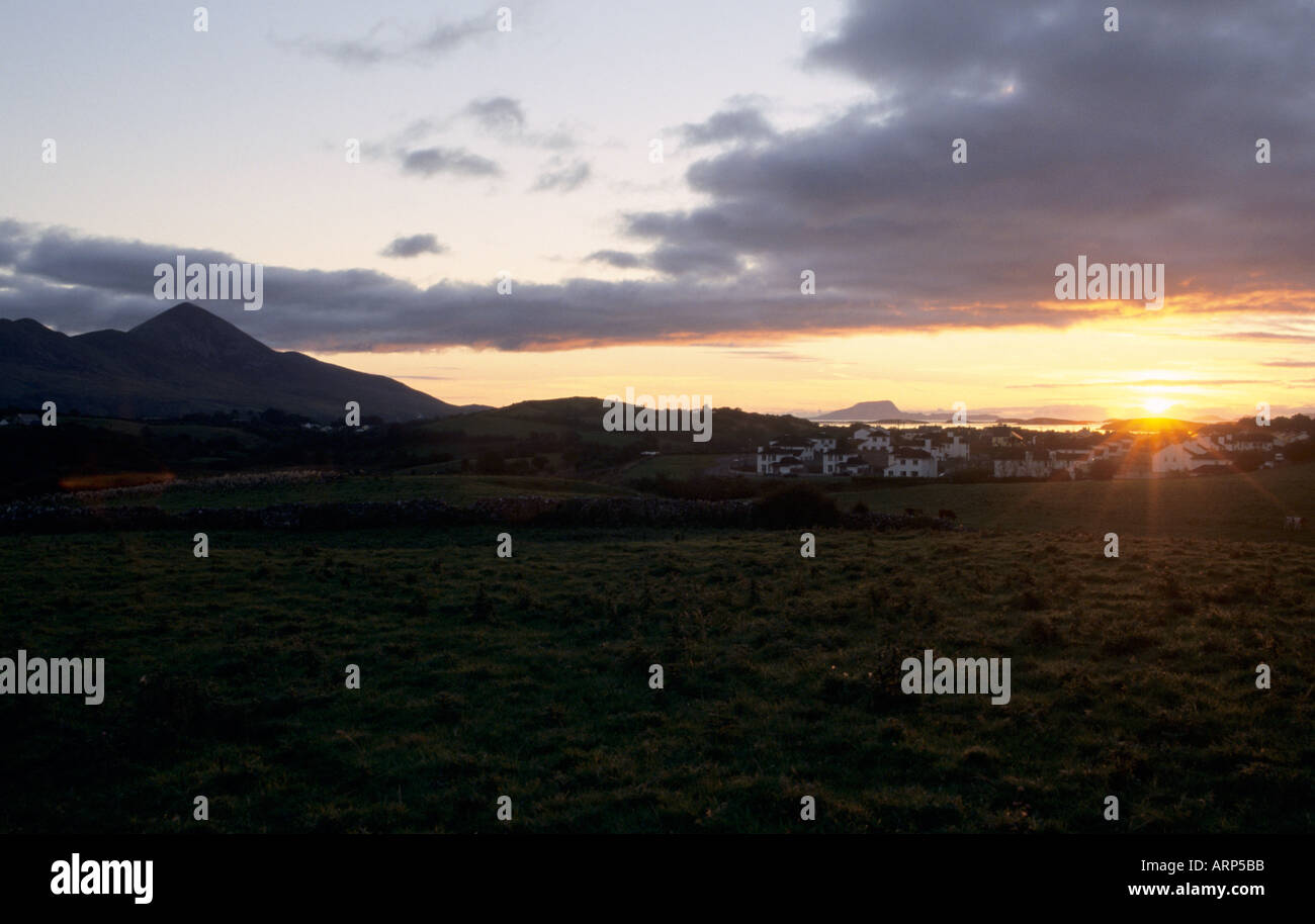 Goldener Sonnenuntergang über Westport Bay mit einem Feld und Westport Quay Stadt vor und Berg auf der linken Seite. Westport Quay, County Mayo, Republik Irland. Stockfoto