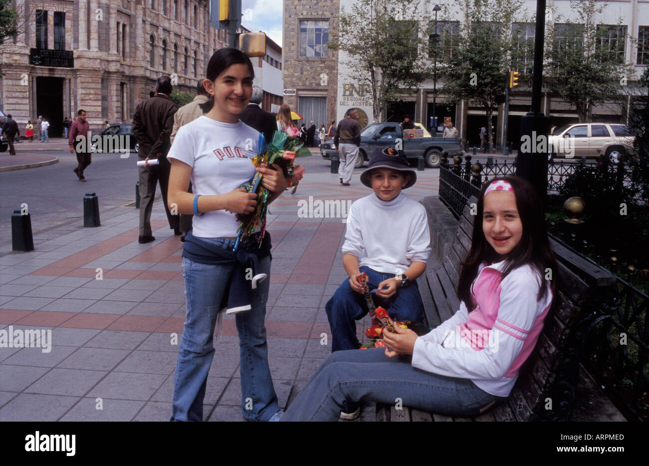 Straßenszene mit drei Mädchen mit Blumen und Schokolade in den Parque Abdon Calderon in der Stadt Cuenca in Ecuador Stockfoto