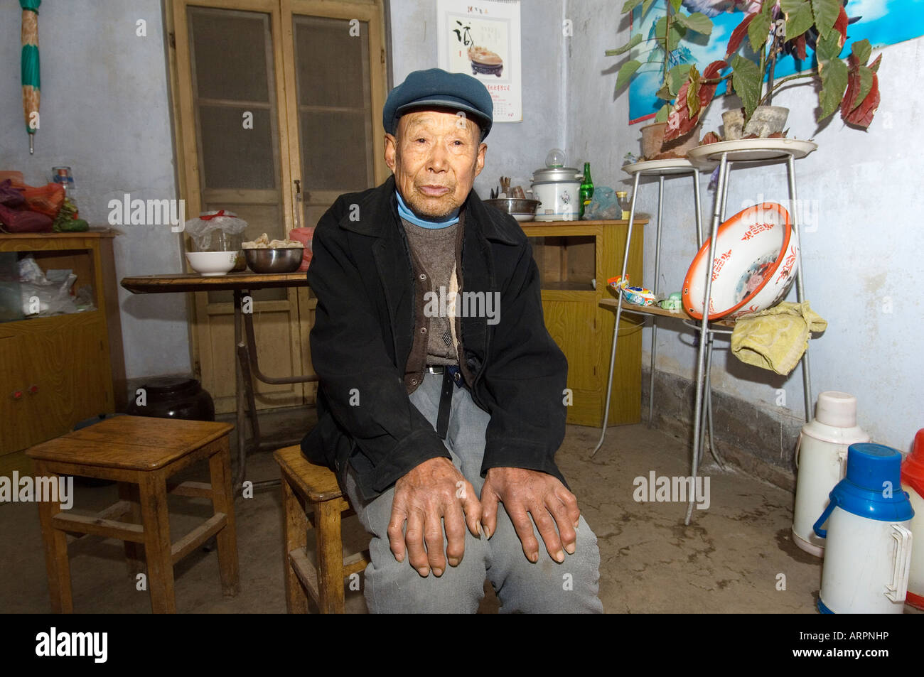 Alte chinesische Mann Bauer sitzen in Landhausküche im Dorf von Poli in der Nähe von Penglai, Provinz Shandong, China Stockfoto