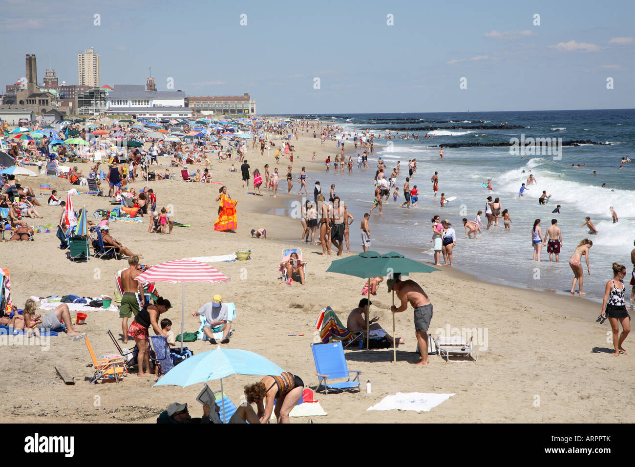 Die Surfline ein Jersey Shore Strand mit Menschen entlang, stehend und planschen im seichten Wasser. Stockfoto