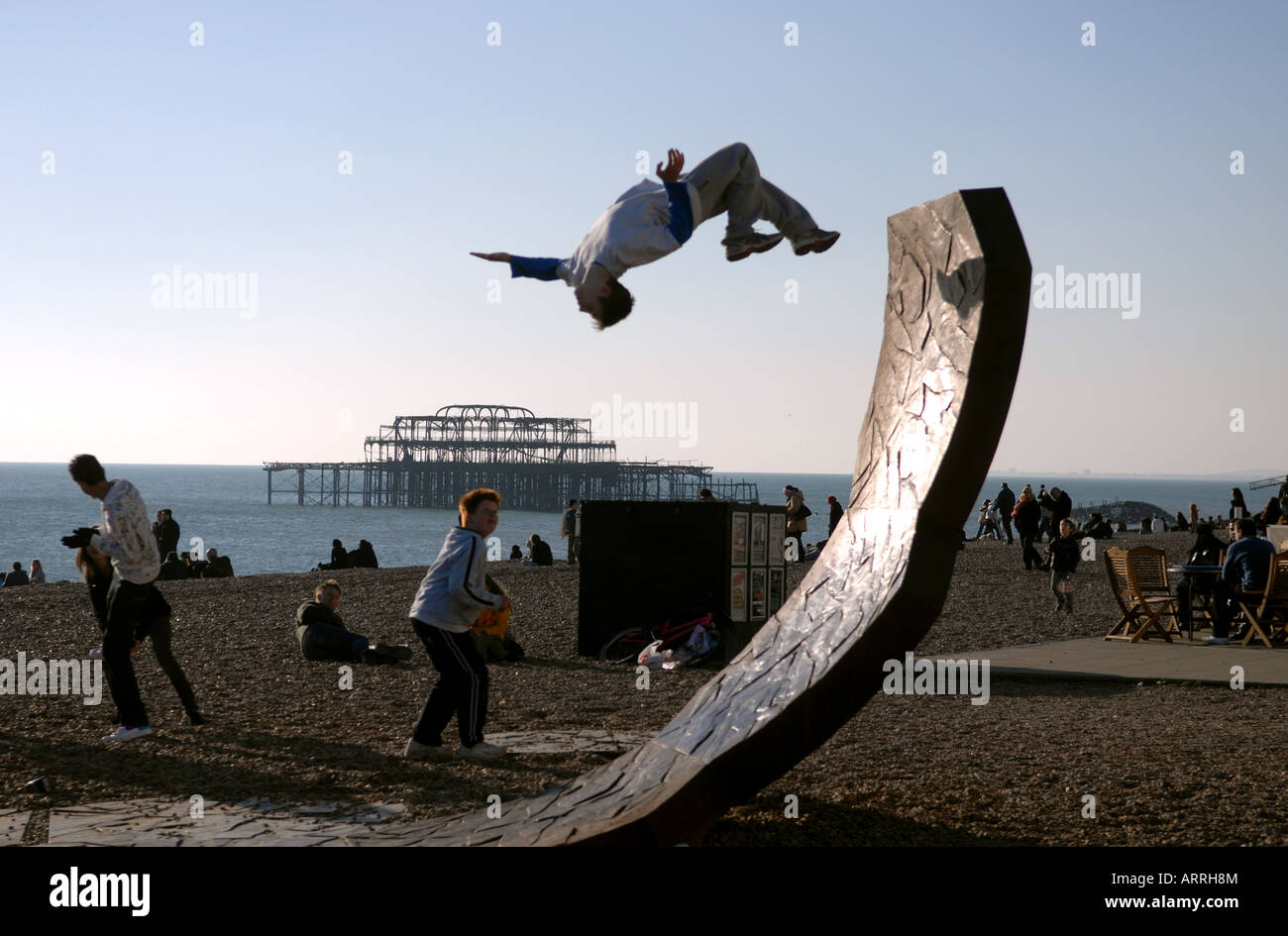 Ein Teenager führt einen Back Flip auf einem Strand von Brighton s Passacaglia Skulptur von Charles Hadcock Stockfoto