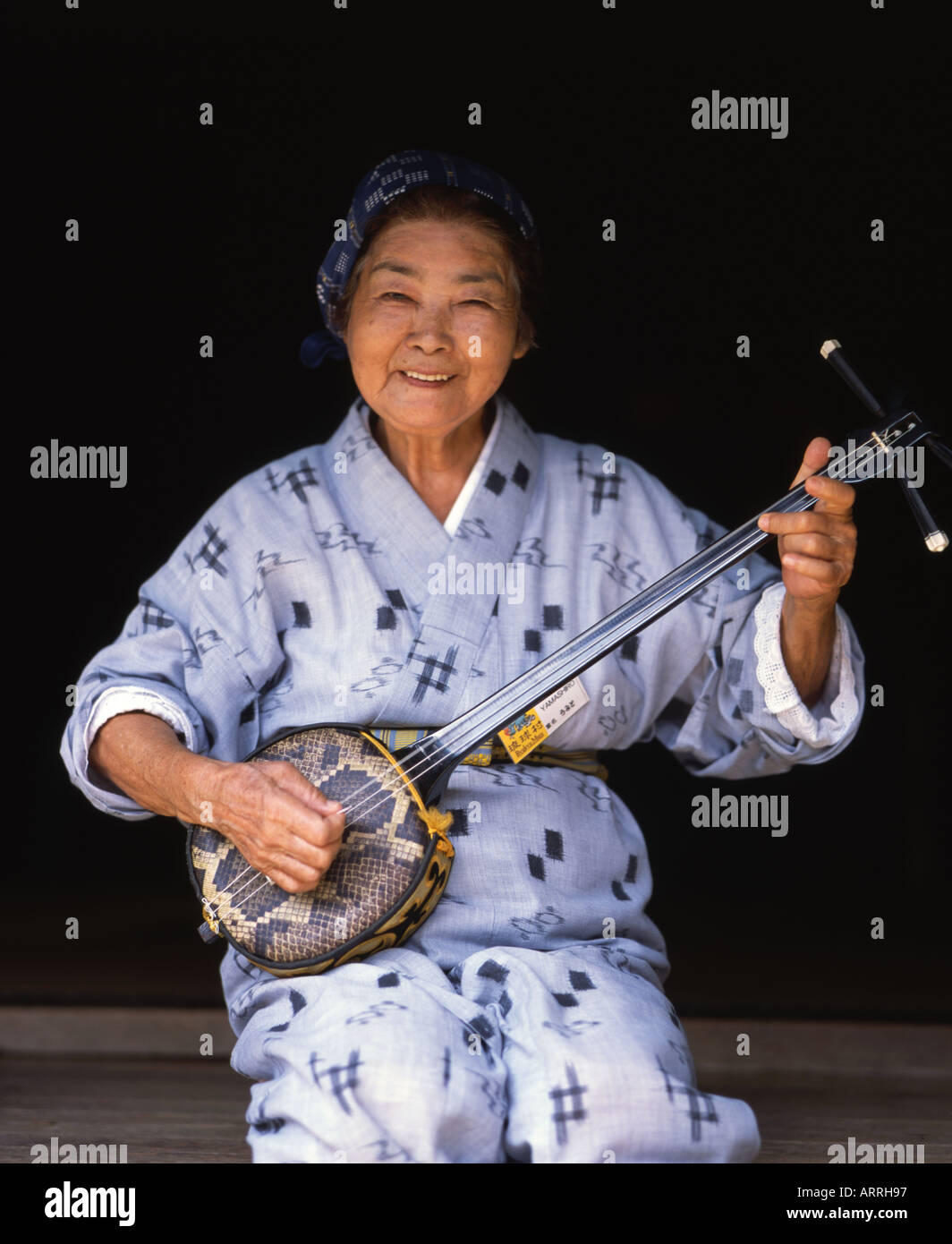 Schöne ältere Okinawan Dame trägt einen traditionellen Yukata Kimono spielt shamisen Stockfoto