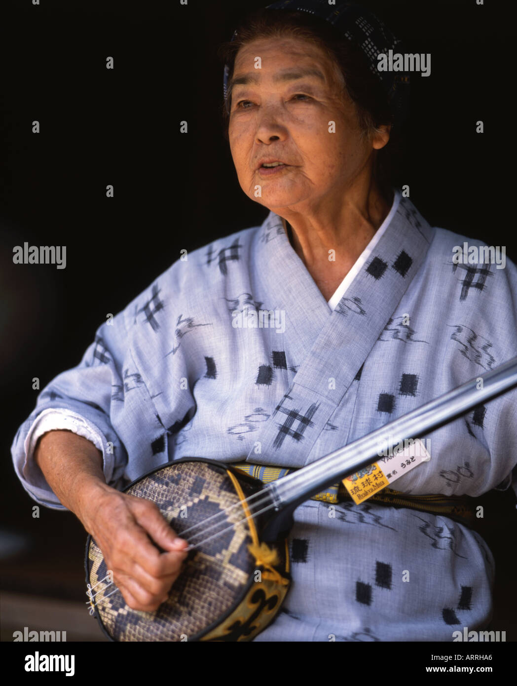 Schöne ältere Okinawan Dame trägt einen traditionellen Yukata Kimono spielt Shamisen eine Okinawan sanshin Stockfoto