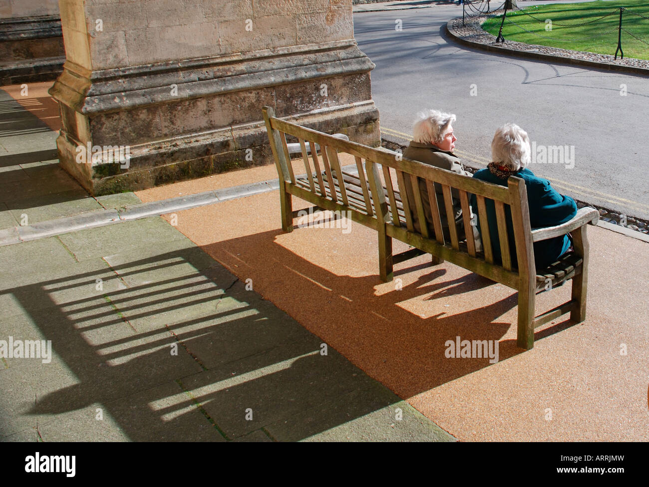 zwei alte Damen saß auf der Bank mit langen Schatten. Stockfoto