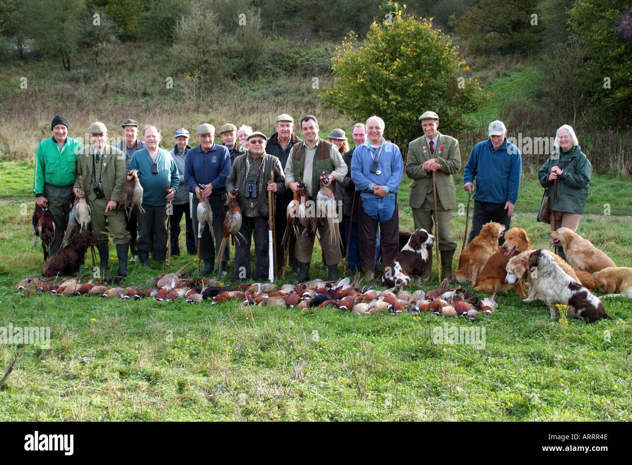 Bauernhof Arbeitnehmer Schläger und Wildhüter und ihren Hunden posieren für ein Gruppenfoto mit der Fasane, eingesackt worden Stockfoto