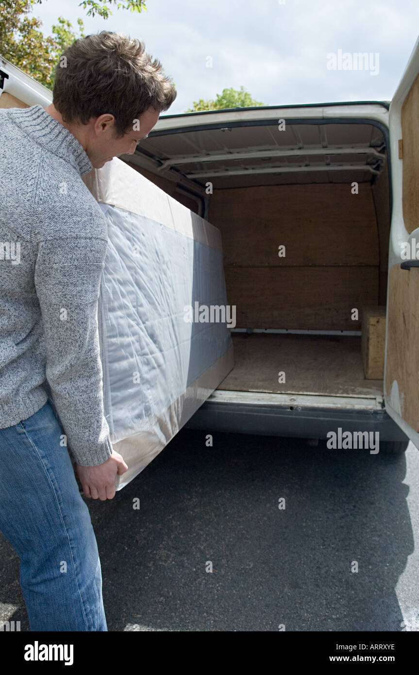 Mann bewegt Matratze aus van Stockfoto