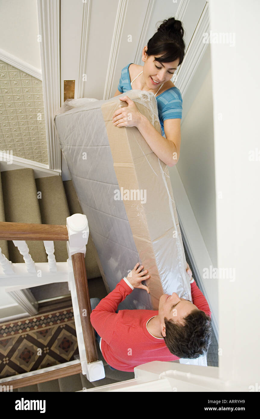 Paar mit Matratze Treppe hinauf Stockfoto