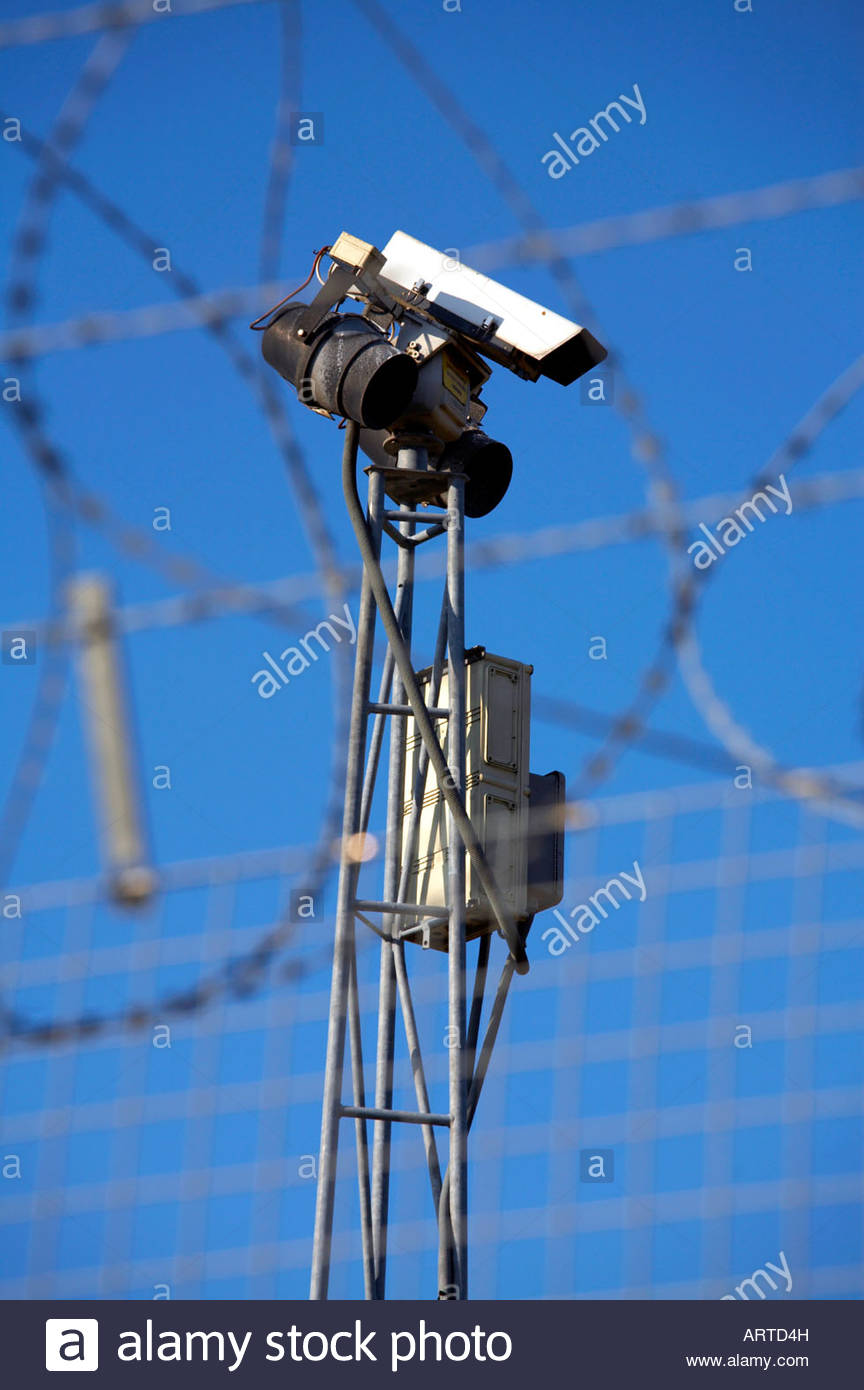 Überwachungskamera hinter einem Zaun mit Stacheldraht Stockfoto