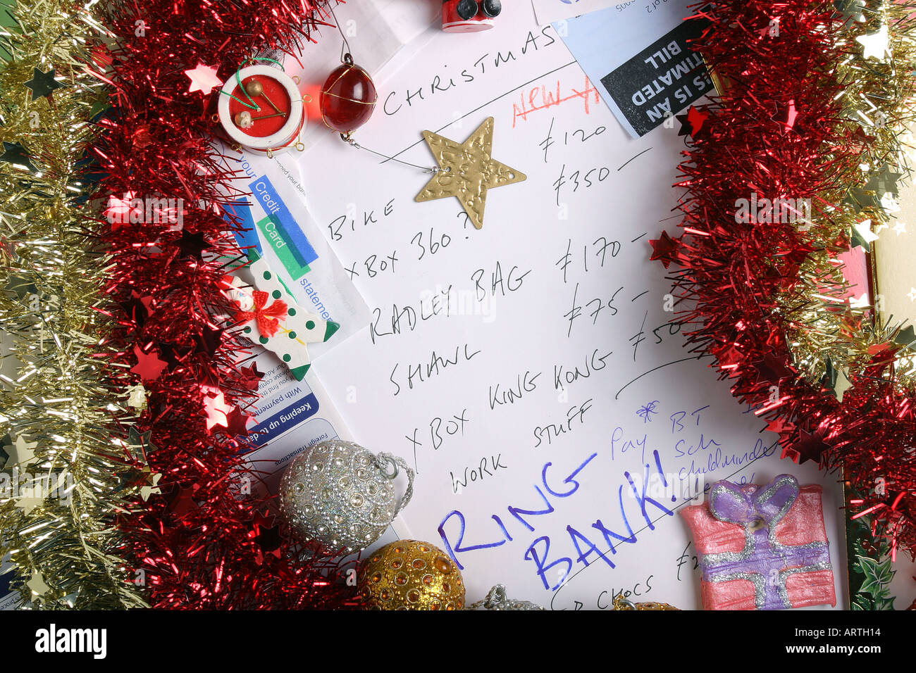 Rechnungen, Kontoauszug, Lametta, Baumschmuck und Kreditkartenabrechnungen umgeben eine Weihnachts-Liste. Stockfoto