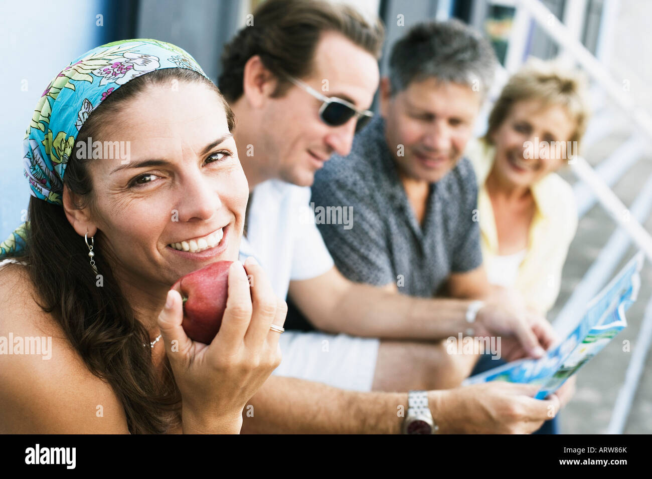 Porträt einer Mitte Erwachsene Frau mit ihren Freunden sitzen neben ihr einen Apfel essen Stockfoto