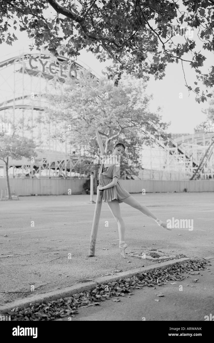Ballerina tanzt auf einem leeren Parkplatz auf Coney Island mit dem Zyklon Steilabfall im Hintergrund Stockfoto