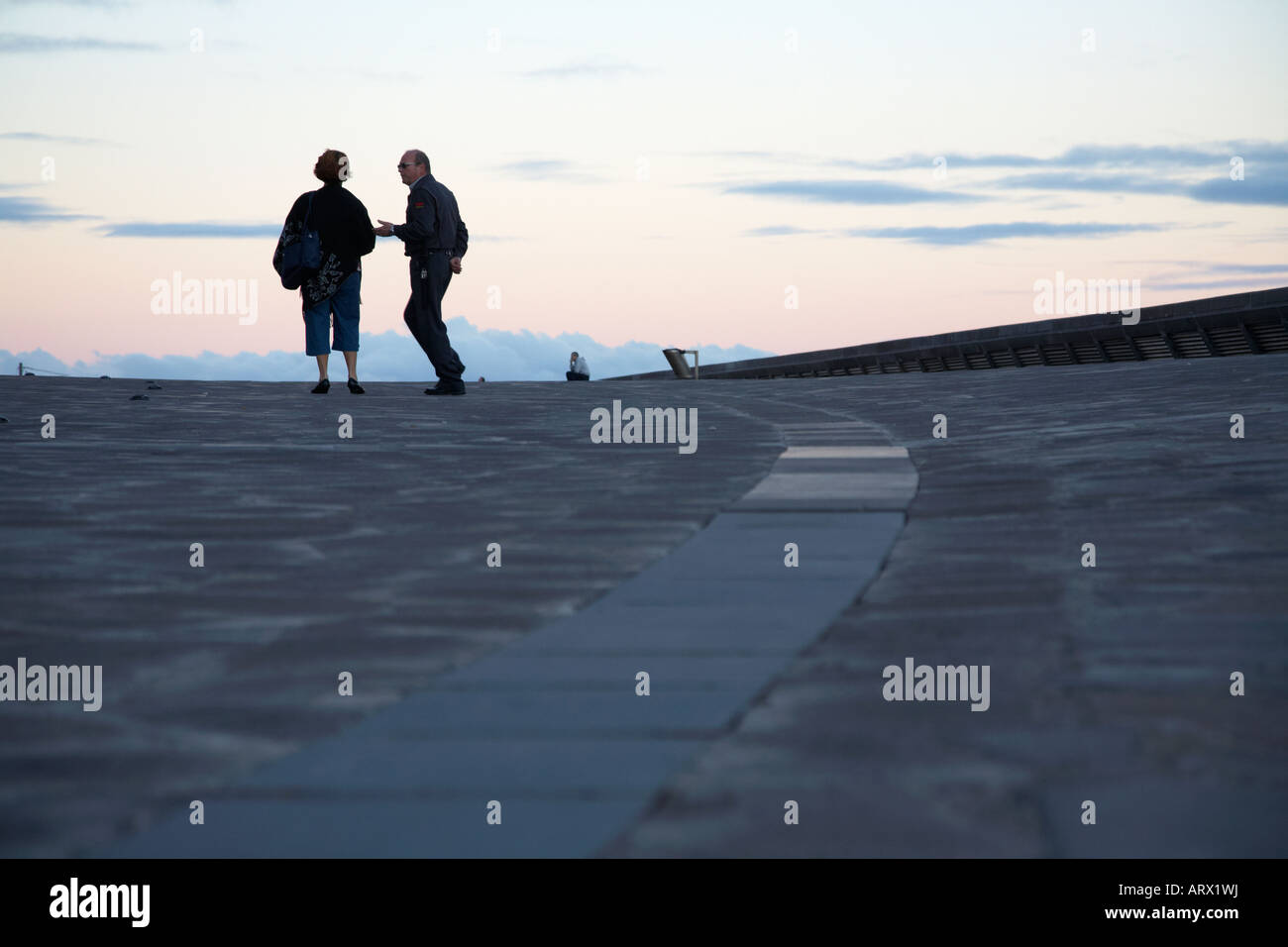 einzelne einsame Frau mit Wachmann im Gespräch mit Männern im fernen Hintergrund in Santa Cruz-Teneriffa-Kanarische Inseln-Spanien Stockfoto