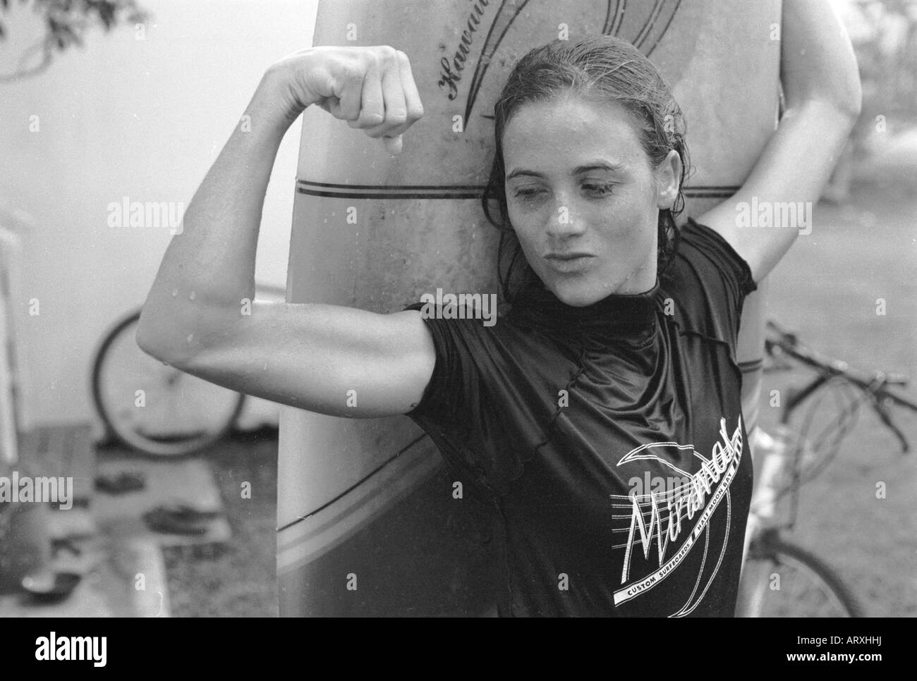 Schwarz / weiß Foto einer jungen Frau Arm zu biegen und hält ein Longboard mit dem anderen Arm. Stockfoto