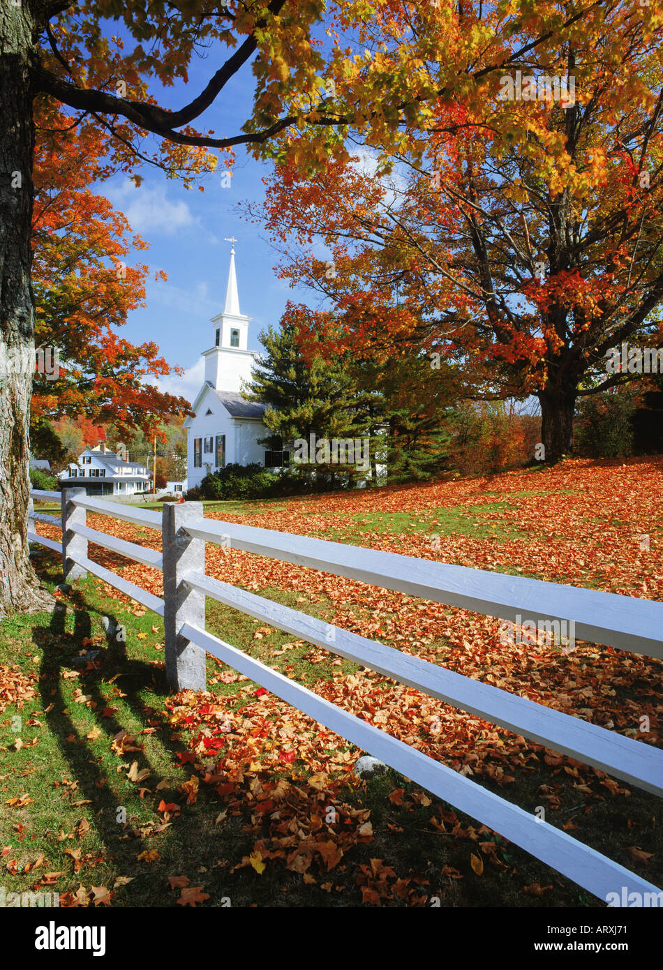 Weißen Lattenzaun und Dorfkirche inmitten Herbstfarben im Fitzwilliam, New Hampshire Stockfoto