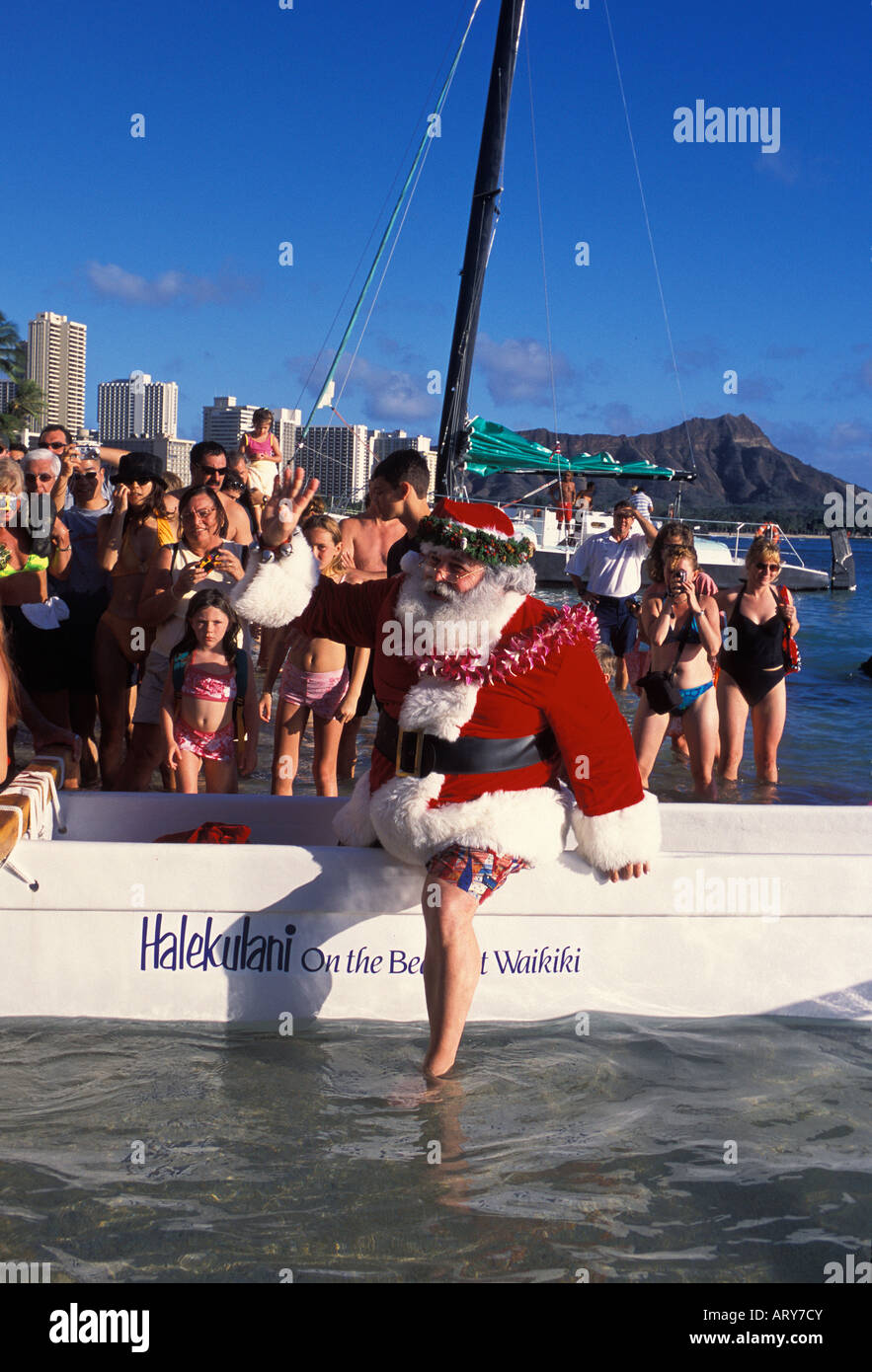 Massen warten Santas von Outrigger Kanu am Heiligabend am Waikiki Beach hinter dem Halekulani Hotel. Stockfoto