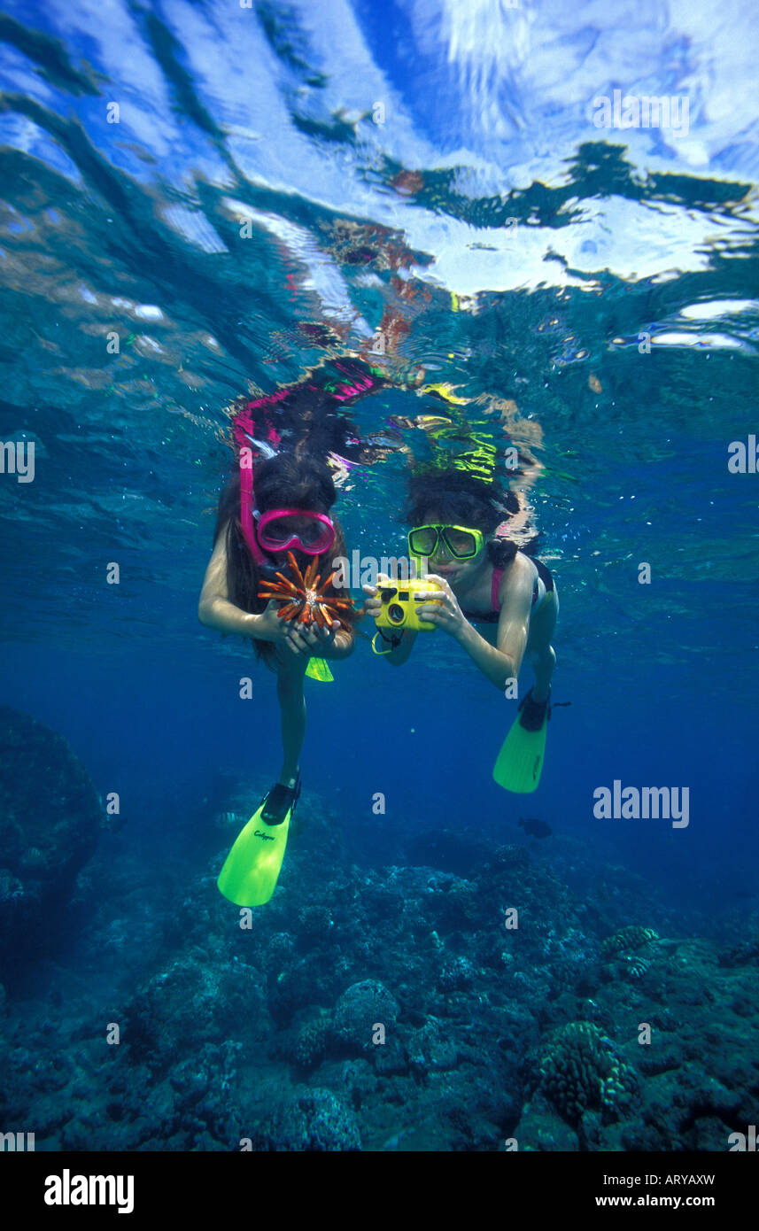 Zwei junge Mädchen (im Alter von 9 & 11) entdecken Sie ein Schiefer-Bleistift-Seeigel auf schönen Korallenriff Hanauma Bay mit einer Unterwasser-Kamera Stockfoto