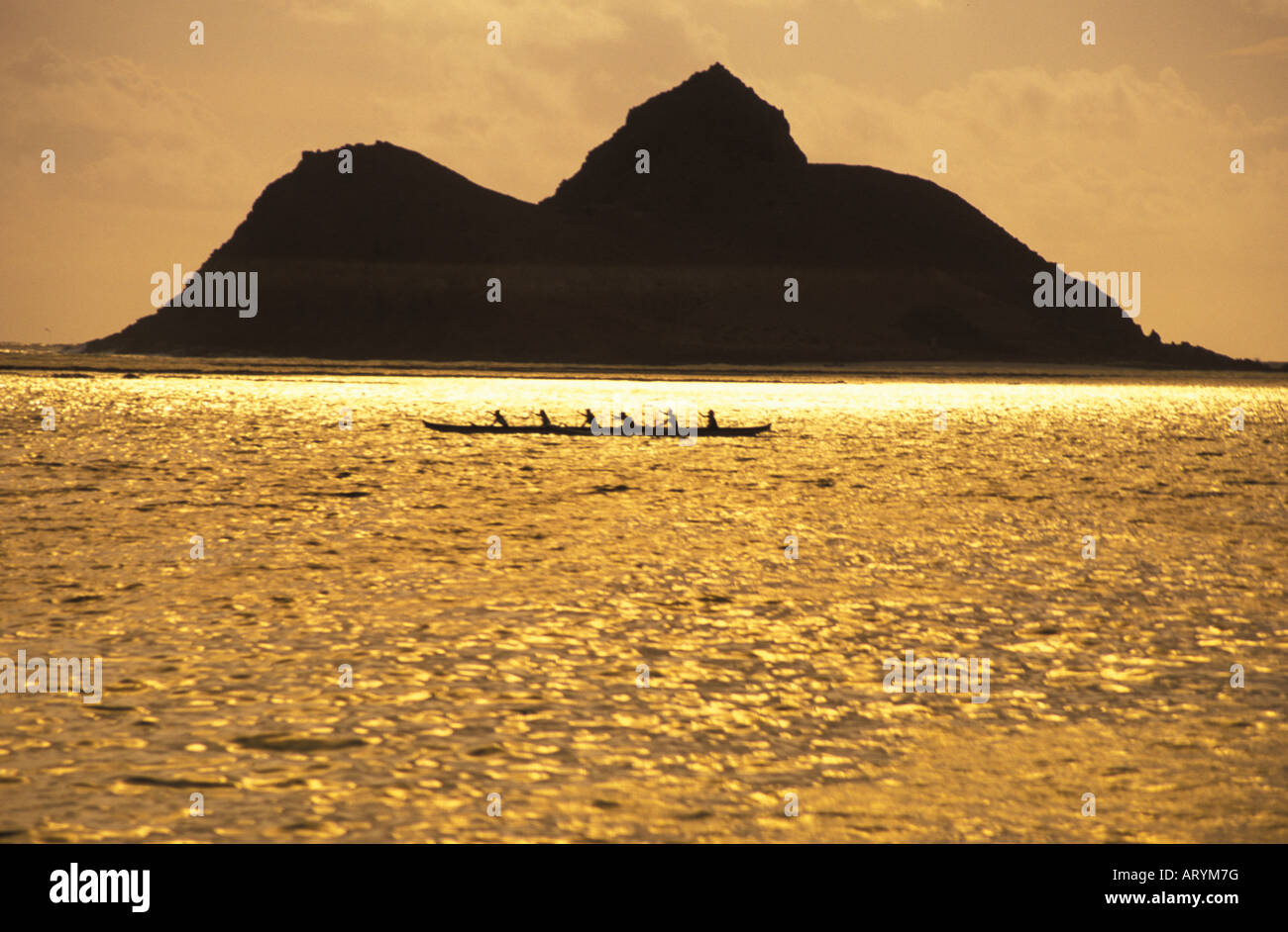 Gruppe paddeln Auslegerkanus im offenen Ozean bei Sonnenaufgang in Lanikai, Windward Oahu mit Moku Lua Insel im Heck Stockfoto