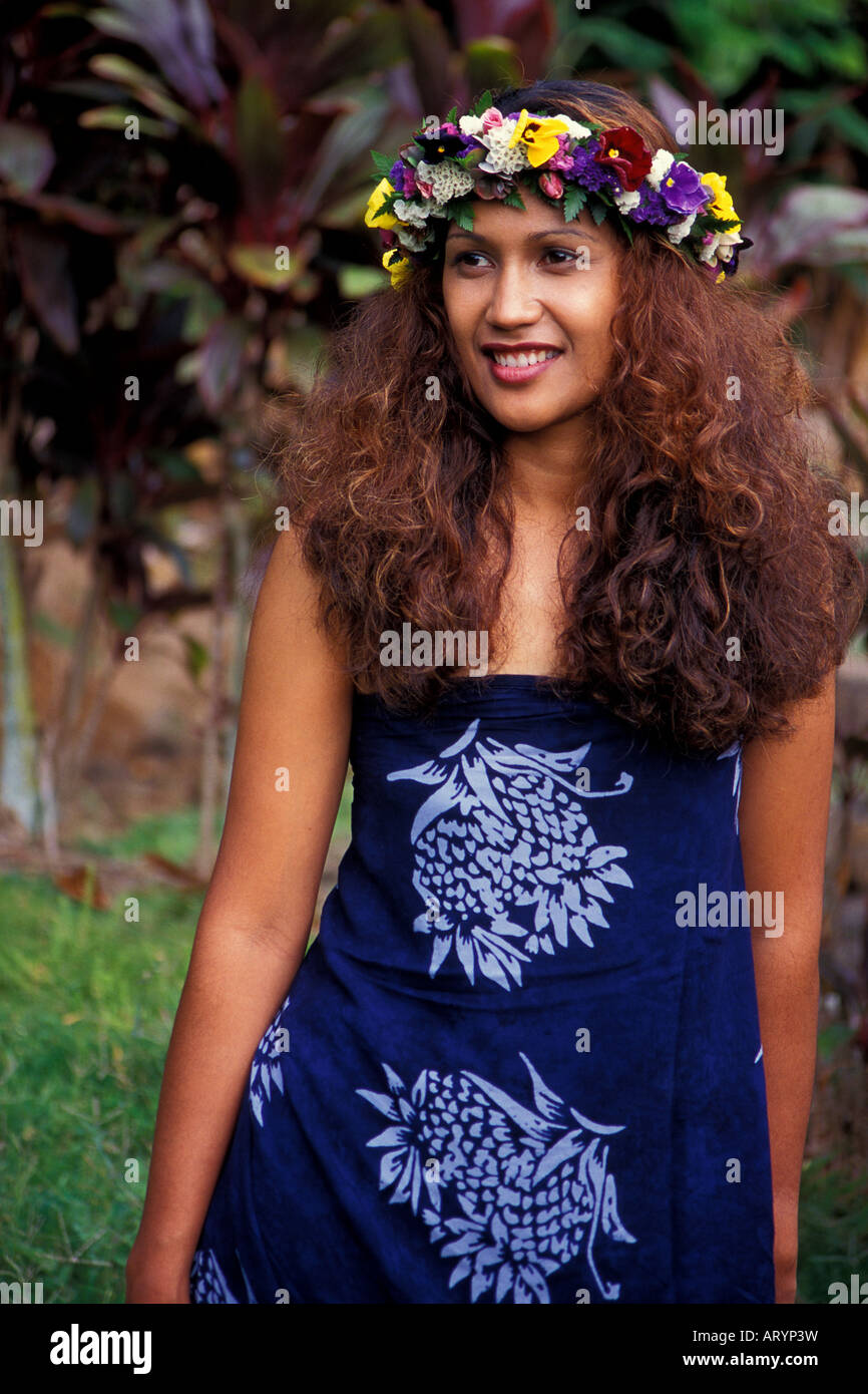 Eine schöne polynesischen Frau tragen eine Haku Lei und eine blaue Pareo lächelt, als sie in einem tropischen Garten geht. Stockfoto