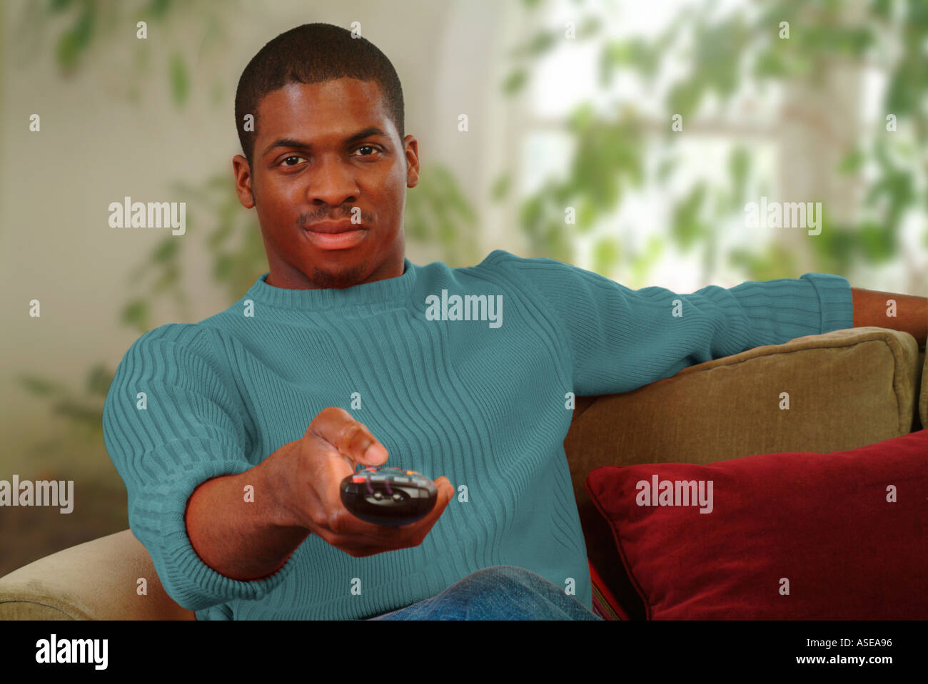 Ein schwarzer Mann Senderwechsel auf dem TV mit Fernbedienung Stockfoto