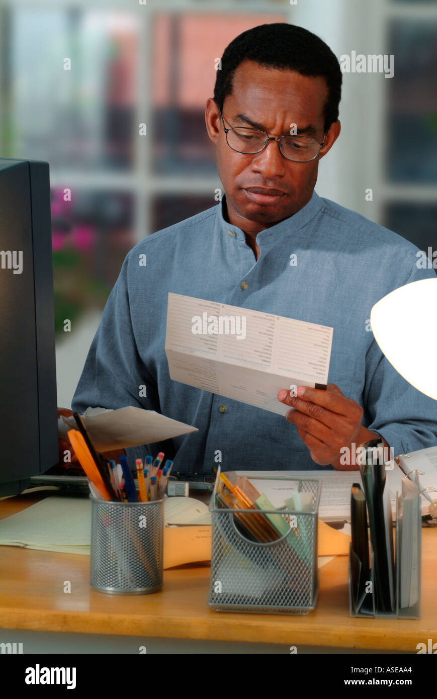 Afrikanische amerikanische Mann arbeiten im home Office und Erhalt einer Rechnung auf dem Postweg Stockfoto