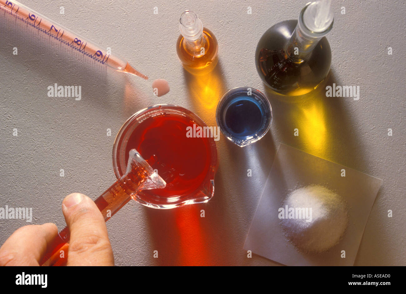 Ein Forscher gießt eine rote Flüssigkeit in ein Becherglas in einer Laborumgebung. Stockfoto