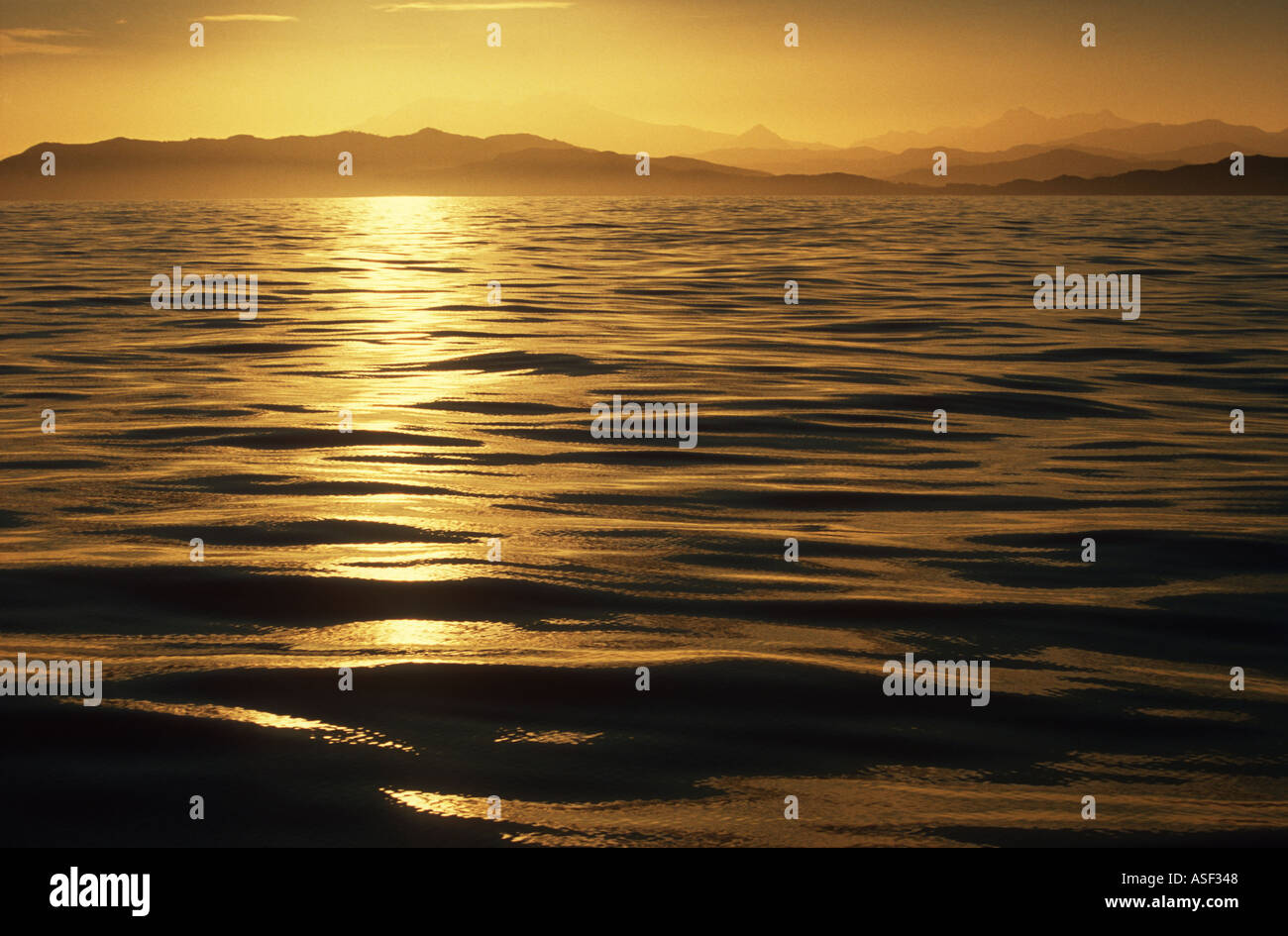 Seascape goldenen Sonnenuntergang aus seidig ruhiges Meer mit Blick auf Berge und Hügel der Raukumara Range East Cape Neuseeland Stockfoto