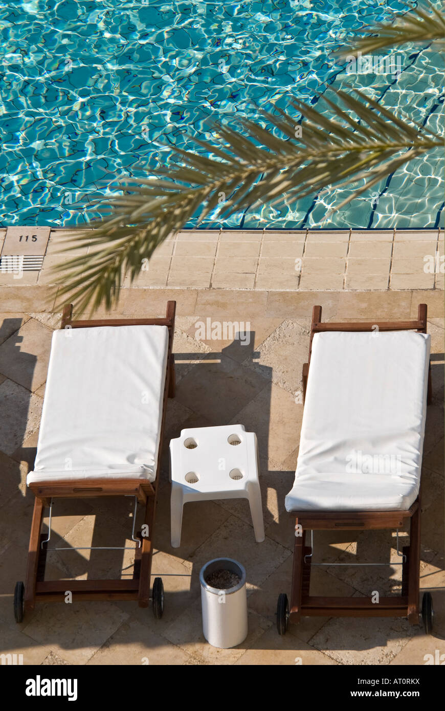 Vertikale erhöhten Nahaufnahme von zwei leeren sauberen weißen Sonnenliegen rund um den Pool ein 5 Sterne Hotel bewertet angeordnet Stockfoto