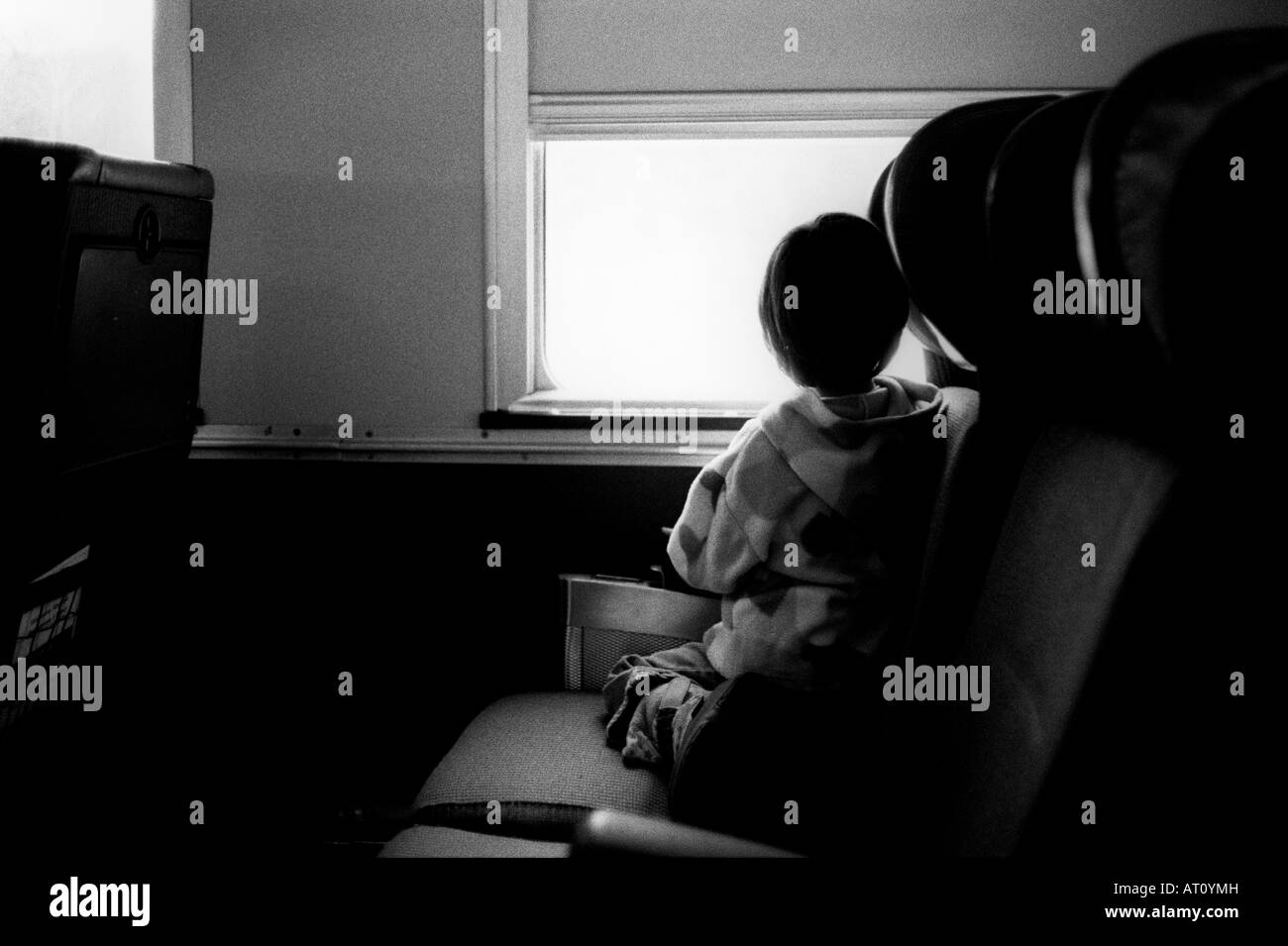 Junges Mädchen kniet auf einem Zug Sitz und Zugfenster schaut. Stockfoto