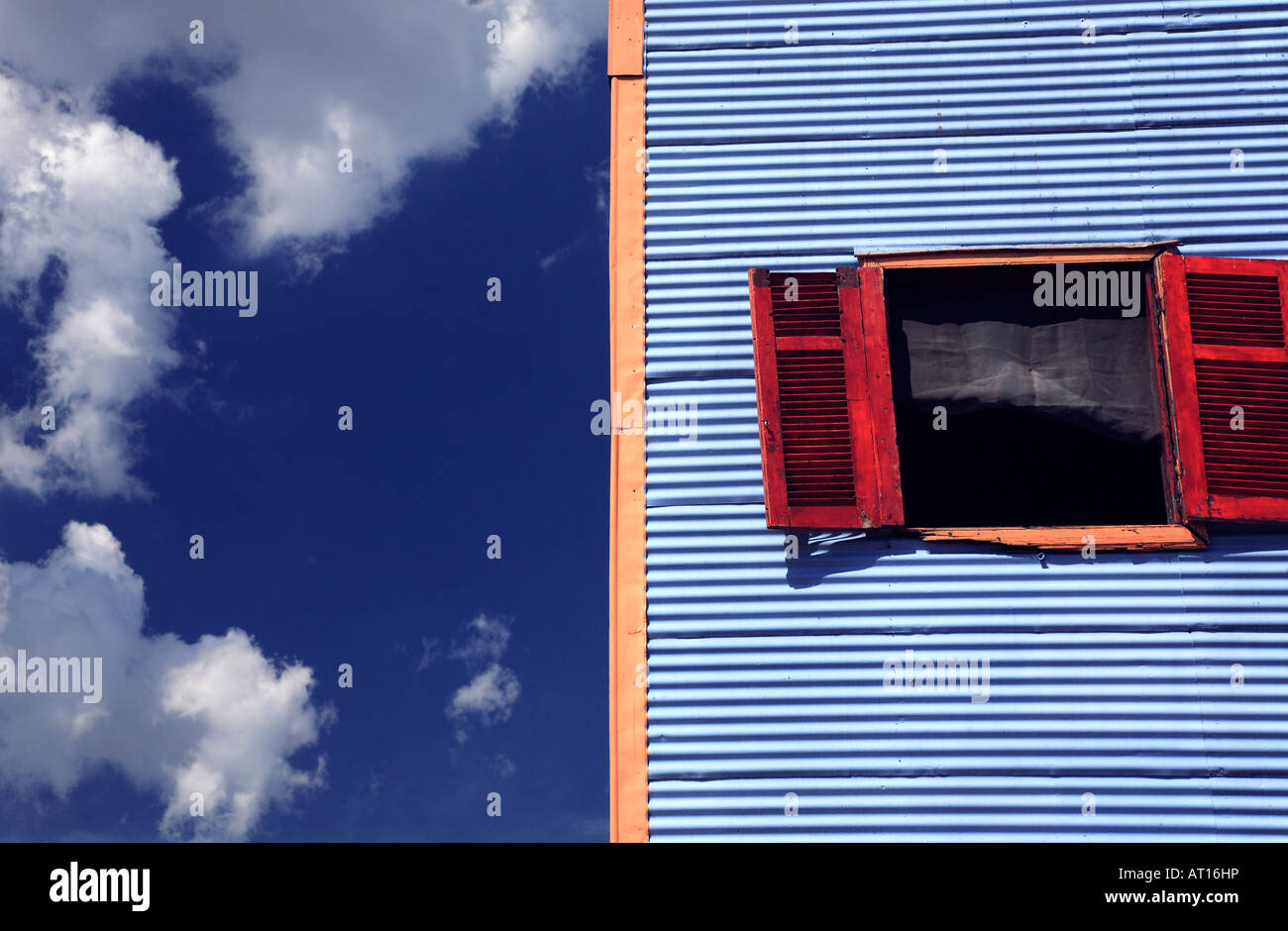 Altes Holz Fenster im metallischen Haus mit tiefblauen Himmel mit Wolken im Hintergrund. Caminito St, La Boca, Buenos Aires, Argentinien Stockfoto