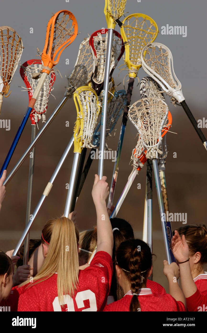 High School-Lacrosse-Spieler heben ihre Lacrosse Sticks zusammen als Team vor dem Start eines Spiels Stockfoto