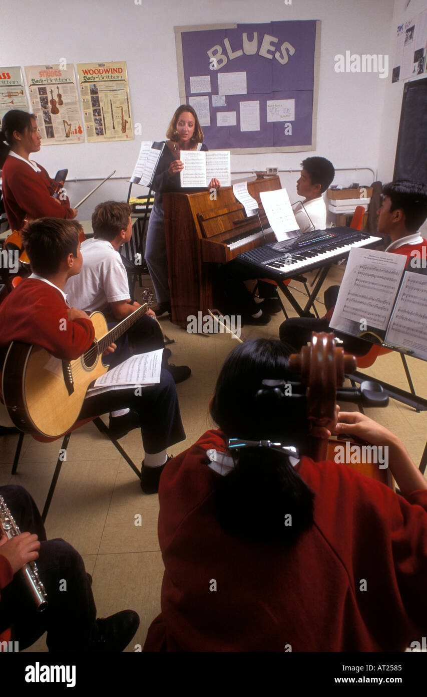 Schule MUSIK GRUPPE BAND KLASSENLEHRER multikulturelle Gruppe von jugendlichen Schüler spielen von verschiedenen Instrumenten im Musikunterricht mit Musik Bücher über steht Stockfoto