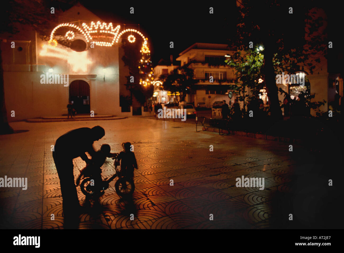 Ein Vater spielt mit seinen Kindern in der Nacht am Heiligabend außerhalb einer Kirche in Nerja Spanien Stockfoto