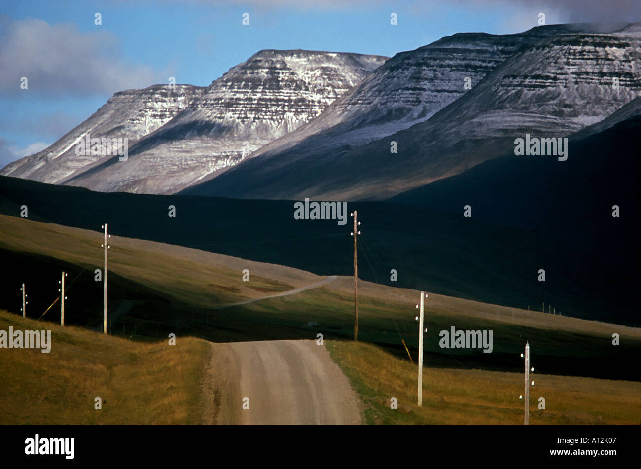 Eine unbefestigte Straße in Island s Vesterland Bezirk mit Schnee bedeckt Hallmundarhraun Berge im Hintergrund Stockfoto