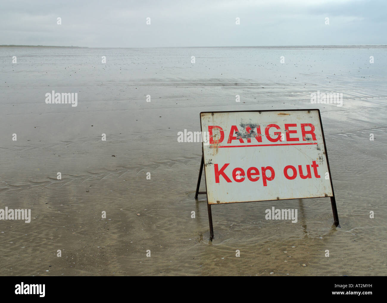 Gefahr fernzuhalten Schild an einem leeren Strand von Pendine Sands bewölkten grauen Himmel Stockfoto