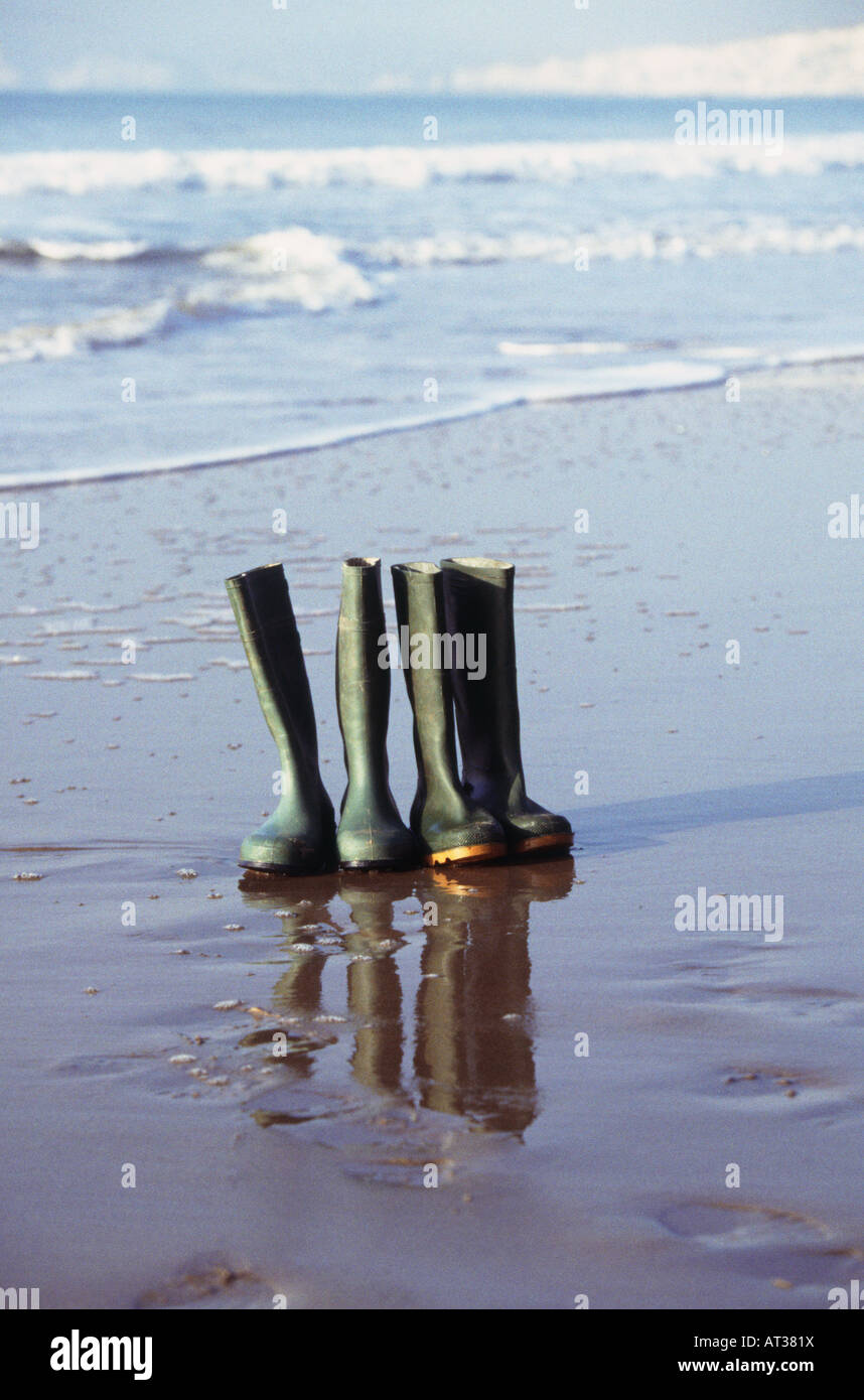 Zwei Paar Gummistiefel aufgereiht am Strand Stockfoto