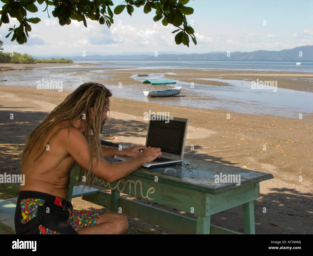 Costa Rica Osa Halbinsel Puerto Jimenez Rastalocken Alterung Surfer e-Mail mit Wifi auf Meer Stockfoto