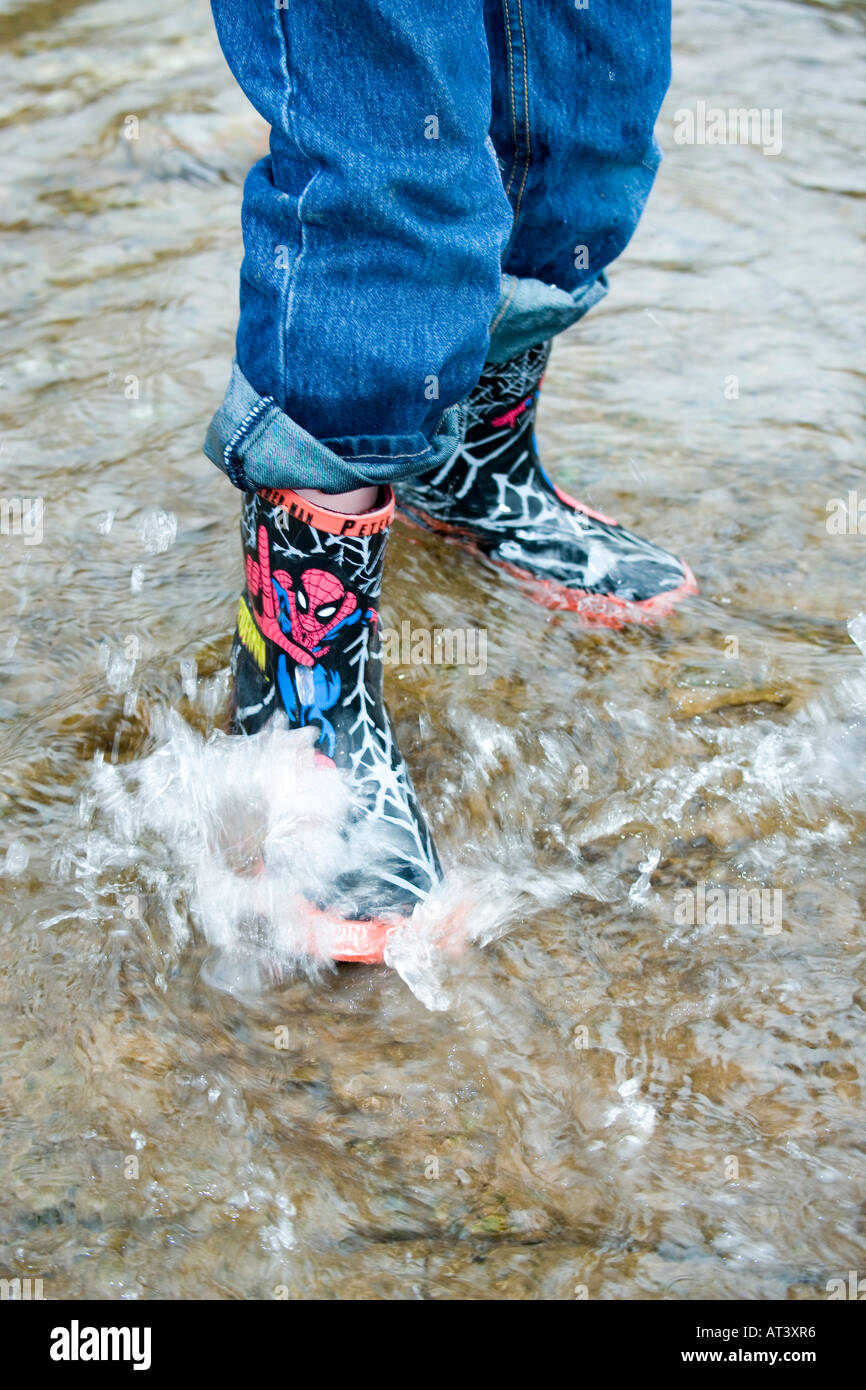 Youngster in Latex Stiefel spielen im Wasser Stockfoto