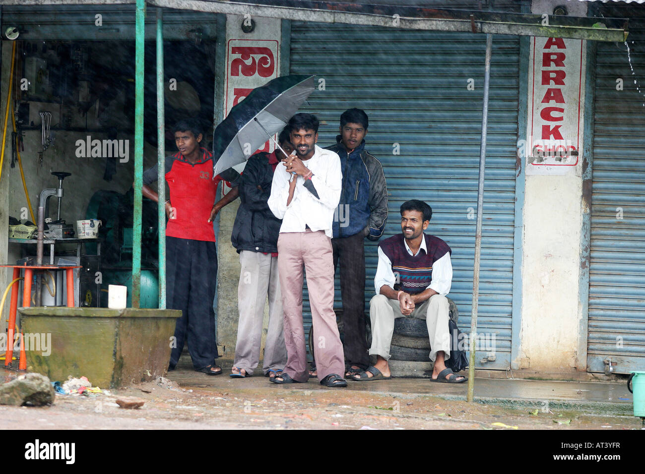 eine Gruppe von jungen Männern Unterschlupf vor dem Monsunregen in dem Land in der Nähe von Mangalore in Indien Stockfoto