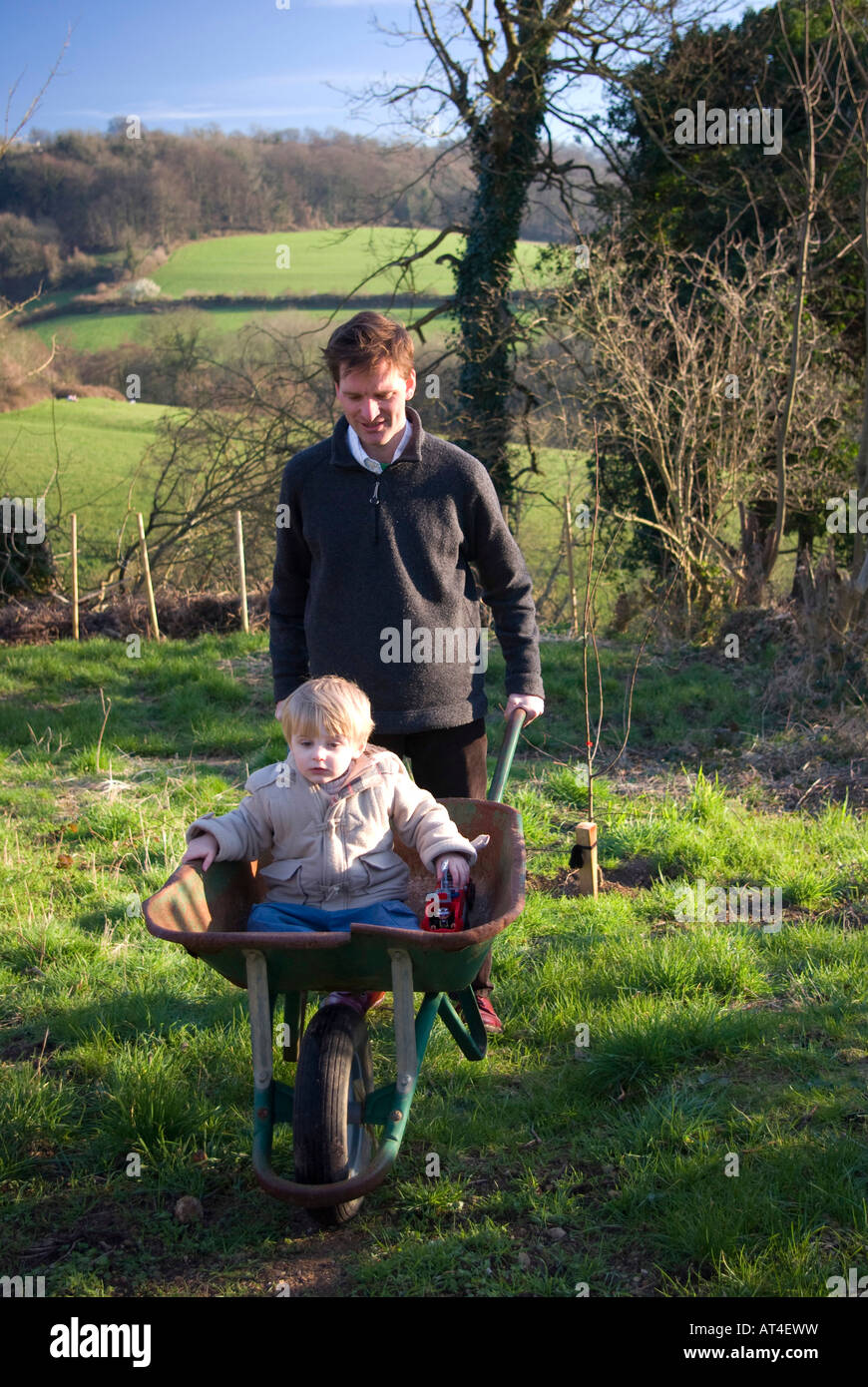 Junge von seinem Vater in einer Schubkarre geschoben Stockfoto