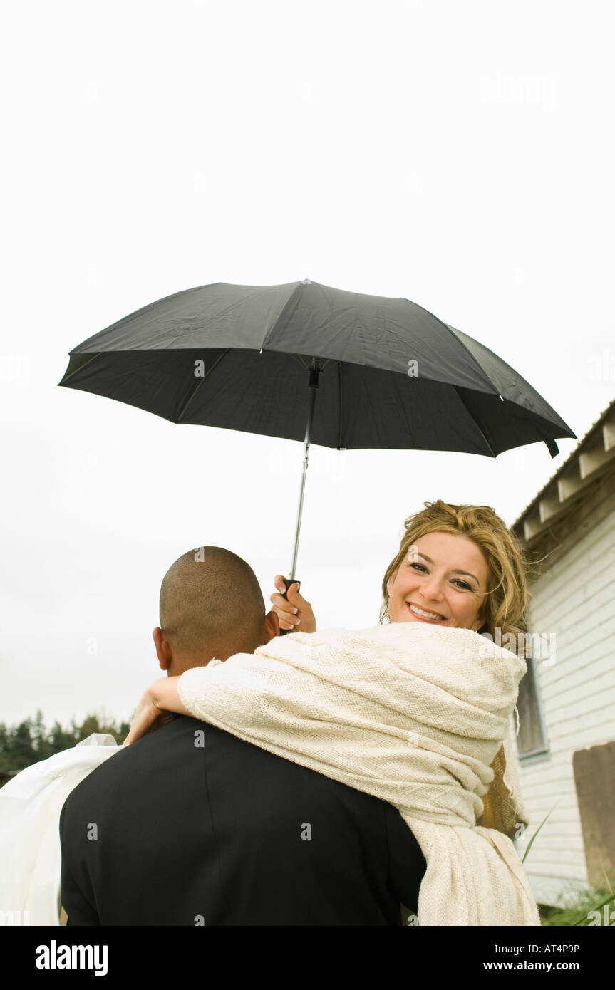 Bräutigam trägt Braut unter Dach Stockfoto