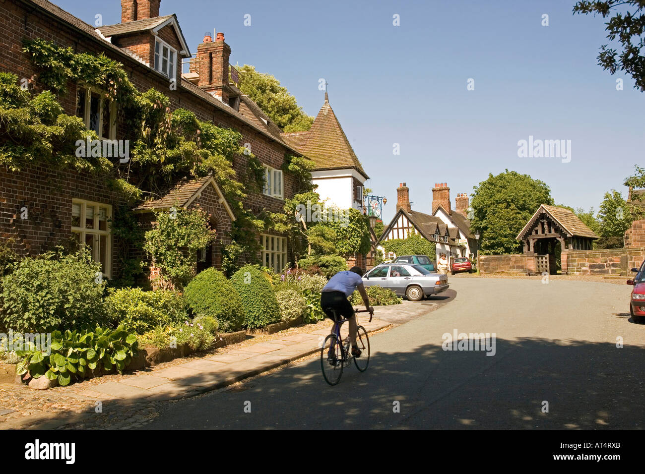 Cheshire Arley Great Budworth Radfahrer auf der Straße durch den Ort, vorbei George Drachen öffentlichen Haus Stockfoto