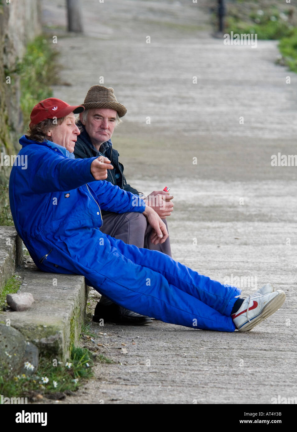 Zwei Männer Wein trinken und reden, auf einer Steinbank sitzend Stockfoto