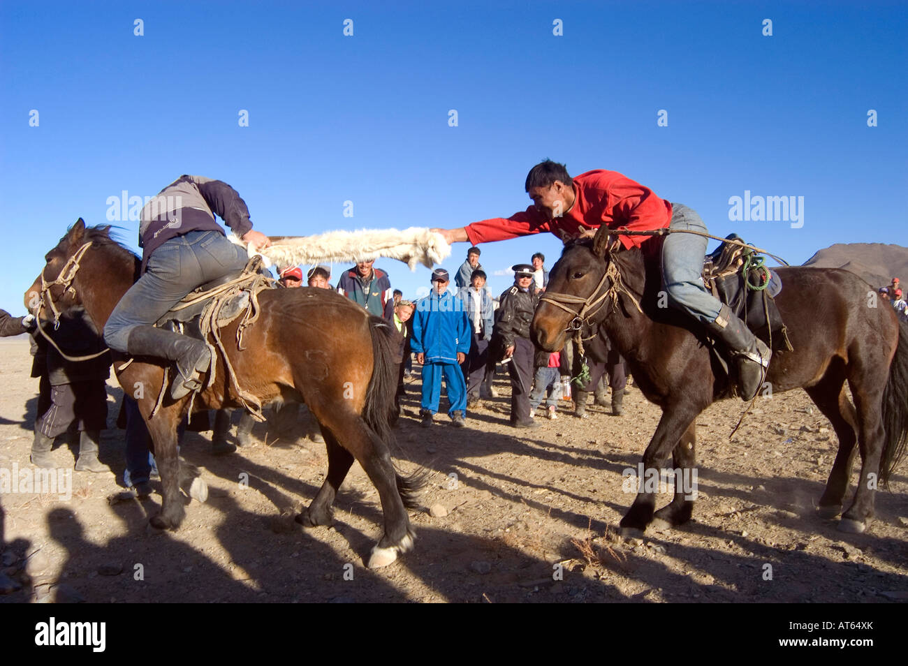 Zwei kasachische Fahrer kämpfen um die Kontrolle einer toten Ziege in einem Spiel von Kokpar oder Bushkashi am jährlichen Adler-Jagd-Festival Stockfoto