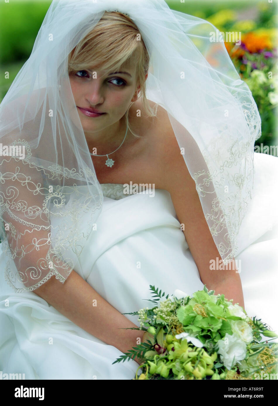 Schöne lächelnde Braut in weiß mit Schleier und Strauß Stockfoto