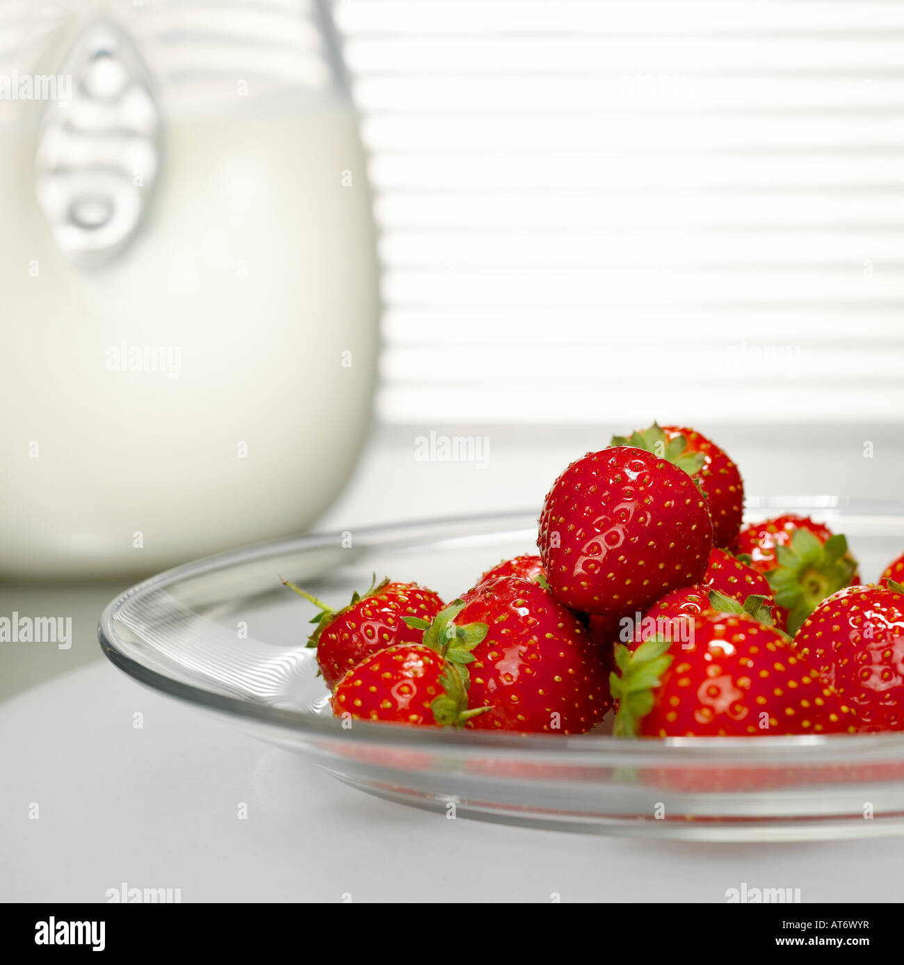 Erdbeeren auf Glasplatte vor Milch Glas, Nahaufnahme Stockfoto