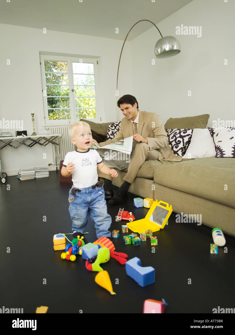 Geschäftsmann und Baby Sohn (12-24 Monate), im Wohnzimmer Stockfoto