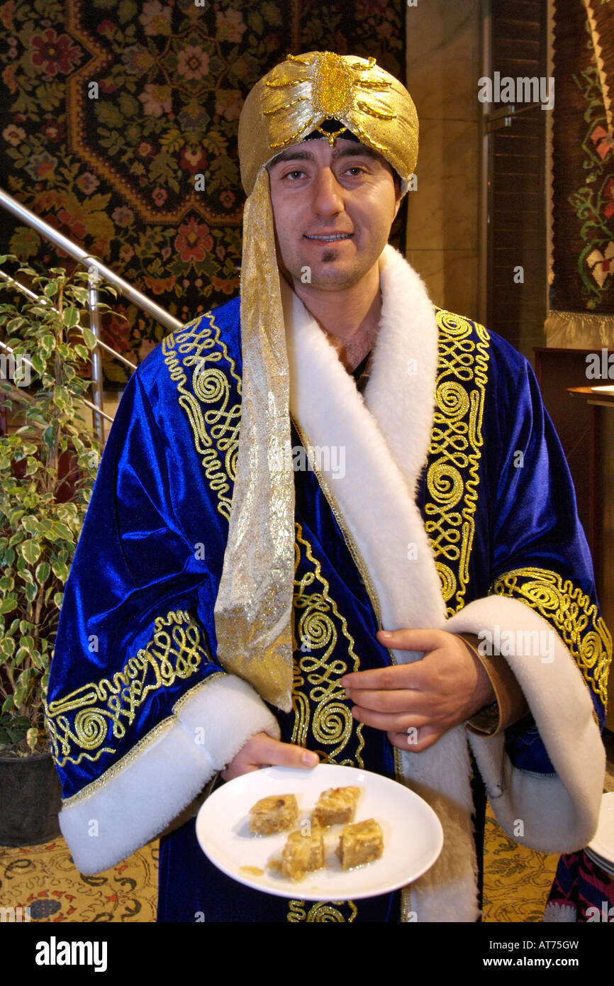 Türkisches Restaurant Gastgeber in Gewand gekleidet und Halteplatte Baklava in Istanbul. Stockfoto