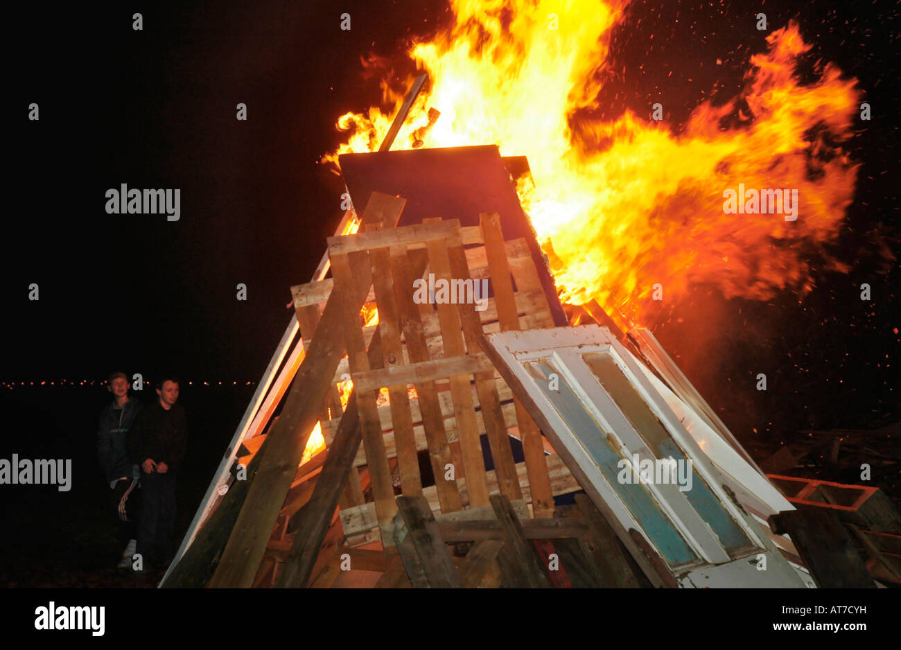 Zwei Kinder zusehen, wie ein großes Lagerfeuer entzündet sich in Flammen Stockfoto